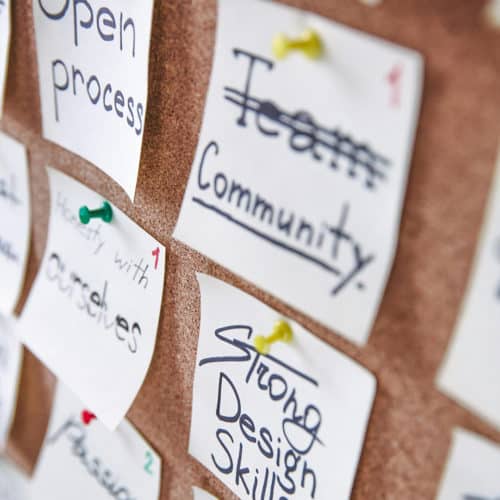 Detailshot einer Kork-Pinnwand. Halb verschwommen sind darauf verschiedene angepinnte Notizzettel mit Schlagworten zu sehen. Sie befassen sie alle mit dem Thema Markenkommunikation.